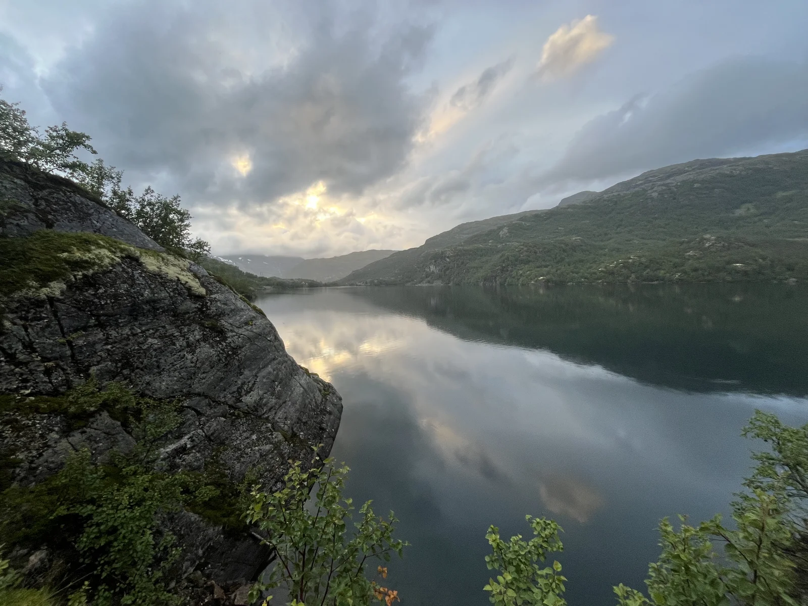 A Norwegian mountain lake reflecting the sky and steep green slopes